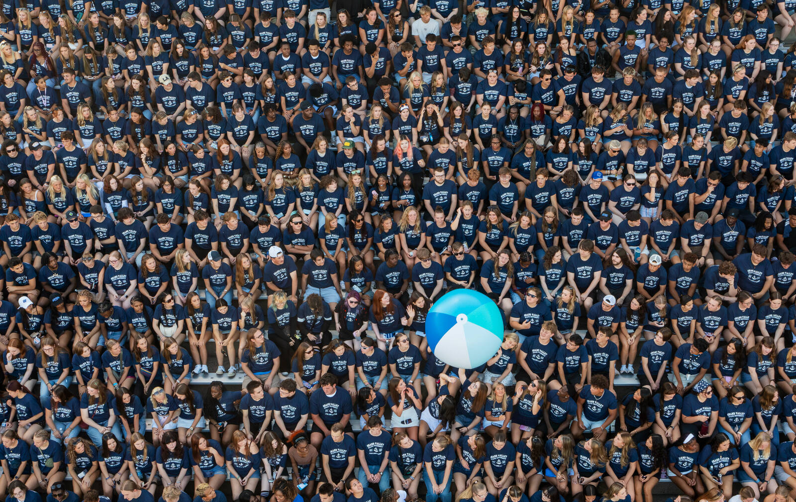 rows of students in blue t-shirts at Lubbers Stadium, beach ball being passed